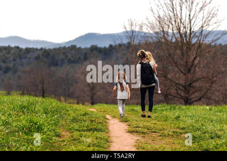 Blue Ridge Mountains sullo sfondo di una madre e le sue due giovani figlie a piedi su un sentiero al Biltmore Estate in Asheville, NC, Stati Uniti d'America Foto Stock