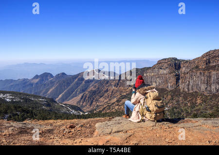 Ragazza tourist si trova sulla cima di una montagna e ammira la vista Foto Stock