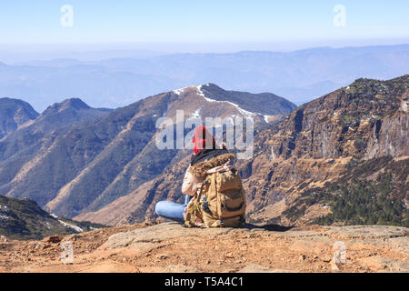 Ragazza tourist si trova sulla cima di una montagna e ammira la vista Foto Stock