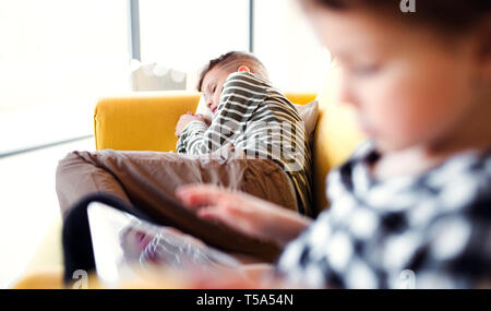 Due bambini di trascorrere del tempo su un divano in interni a casa. Foto Stock