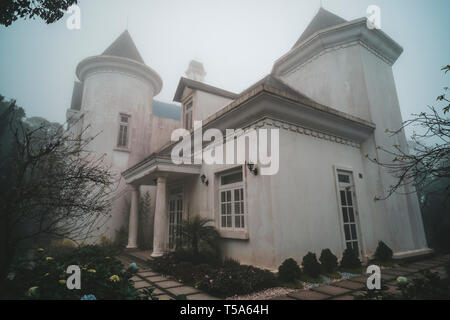 Tradizionale castello francese a Ba Na sulle colline vicino a Da Nang in Vietnam. Antico palazzo cupo nella nebbia nella foresta Foto Stock