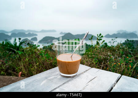 Caffè o tè sulla tabella delle isole e delle montagne. Tradizionale vietnamita il caffè con il latte condensato in un bicchiere di vetro trasparente sullo sfondo di beau Foto Stock
