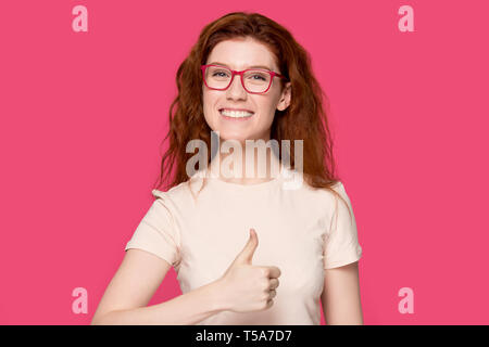 Sorridente i Capelli rossi ragazza in bicchieri mostra pollice in alto Foto Stock