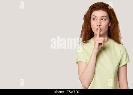 I Capelli rossi ragazza tenere il dito in bocca raccontano di vendita Foto Stock