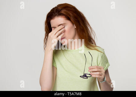 Stanchi i Capelli rossi ragazza togliere i bicchieri che soffrono di problemi di vista Foto Stock