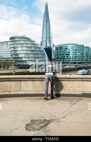 Una persona appoggiata su un parapetto e ammirate edifici iconici sulla South Bank di Londra. Foto Stock