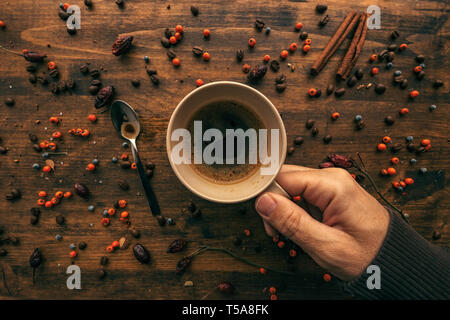 Maschio di mano azienda tazza da caffè, vista dall'alto di una bevanda calda in una tazza sul tavolo di legno Foto Stock