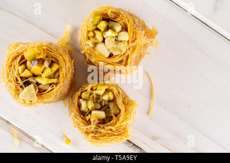 Gruppo di tre tutto il dolce baklava libanese pezzo bird nest varietà flatlay su legno bianco Foto Stock