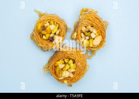 Gruppo di tre tutto il dolce baklava libanese pezzo bird nest varietà flatlay isolato su sky sfondo blu Foto Stock