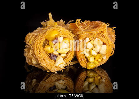 Gruppo di due interi dolce baklava libanese pezzo bird nest varietà isolate su vetro nero Foto Stock