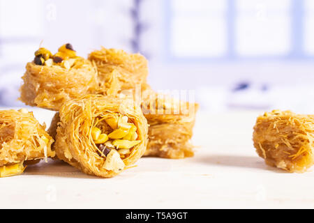 Il gruppo di sette tutta la dolce baklava libanese pezzo bird nest varietà con finestra blu in una cucina bianca Foto Stock