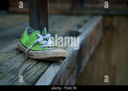 Vecchio puzzolente indossato classic sneaker perso su una strada di città Foto Stock