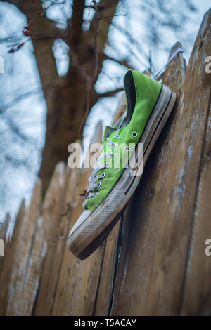 Vecchio puzzolente indossato classic sneaker perso su una strada di città Foto Stock