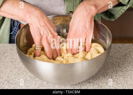 Donna di punzonatura scimmia giù di pasta di pane, prima della formatura delle palline. (MR) Foto Stock