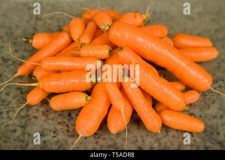 Pila di lavare le carote arancione su un vetro tagliere in cucina Foto Stock