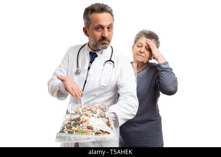 Medico presentando un sacchetto di pillole di preoccupato per il paziente di sesso femminile di toccare la fronte con palm isolato su bianco di sfondo per studio Foto Stock