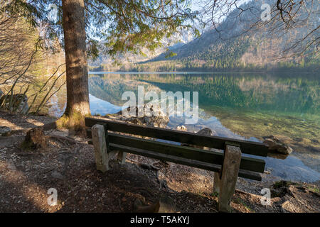 Svuotare panca in legno sulla riva della Vorderer Langbathsee vicino Ebensee, OÖ, Austria, con il grande paesaggio riflettendo sull'acqua cristallina Foto Stock