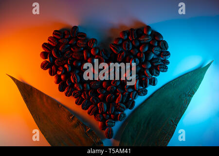 I chicchi di caffè sono evidenziate con neon colorati rivestiti in forma di cuore e foglie Foto Stock