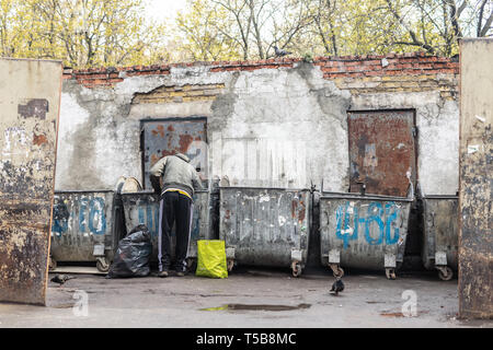 Kiev, Ucraina - Aprile 20th, 2019: senzatetto mendicante alla ricerca di cibo in contenitori di rifiuti in strada della citta'. Disoccupazione e povertà. Foto Stock