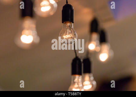 Vista ravvicinata di vintage luci decorative della lampadina incandescente sul soffitto in ambienti chiusi. Lampadine trasparenti incandescente con la luce calda. Foto Stock