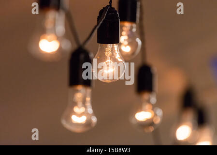 Vista ravvicinata di vintage luci decorative della lampadina incandescente sul soffitto in ambienti chiusi. Lampadine trasparenti incandescente con la luce calda. Foto Stock