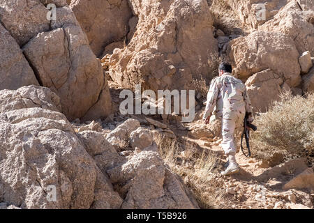 Lonely iraniano guardia rivoluzionaria con una pistola la visione di contrabbandieri proveniente da Byara, Iraq, per trasportare le merci di contrabbando in Iran, Kermanshah Provincia, Iran Foto Stock