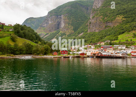 Le piccole case del comune sul fiordo, fotografata da una crociera turistica traghetto in partenza in estate da Flam, Norvegia vista di un villaggio sul bordo Foto Stock