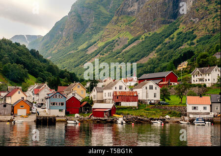 Le piccole case del comune sul fiordo, fotografata da una crociera turistica traghetto in partenza in estate da Flam, Norvegia vista di un villaggio sul bordo Foto Stock