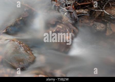 Una lunga esposizione del torrente impetuoso su alcune pietre Foto Stock
