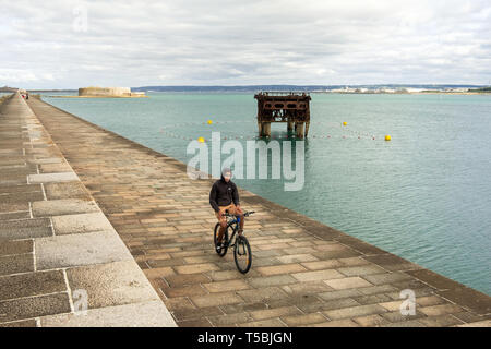 Cherbourg-Octeville, Francia - 27 agosto 2018: un giovane uomo su una mountain bike su una fortificazione dyke nel porto di Cherbourg. La Normandia, Francia Foto Stock