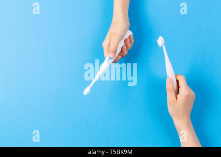 Kid le mani con gli spazzolini da denti elettrici su sfondo blu Foto Stock