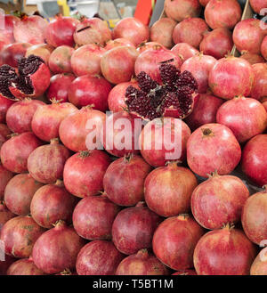 Mature e frutti rossi melograno e diviso in quattro parti, contro lo sfondo di melograno frutto rivestita in righe Foto Stock