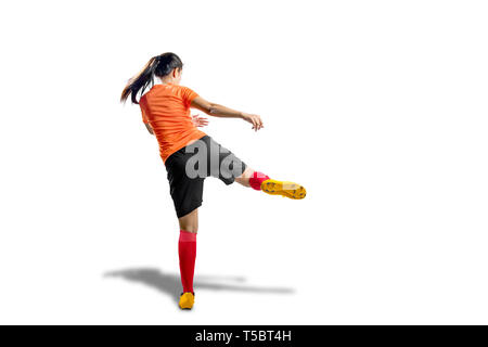 Vista posteriore di asian football player donna in maglia arancione con calci la posizione della sfera isolate su sfondo bianco Foto Stock