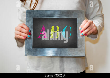 Bambino in possesso di una lavagna con il testo ABC in lettere colorate Foto Stock
