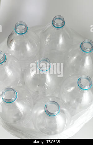 Vista superiore di diverse bottiglie vuote di litro e mezzo di acqua minerale, senza tappi, solo con il blu anello di tenuta, all'interno di una apertura in plastica trasparente Foto Stock