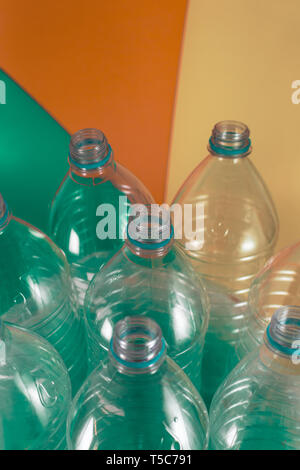 Un pacco di 8 vuoto e materiale plastico riciclabile e bottiglie di acqua, con n. di tappi di tenuta blu, in un sacchetto di plastica su un colore dai toni pastello del mare verde, beige e Foto Stock