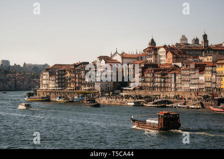 Città vecchia di Porto sul fiume Douro con imbarcazioni turistiche e traghetto al tramonto, Portogallo. Foto Stock