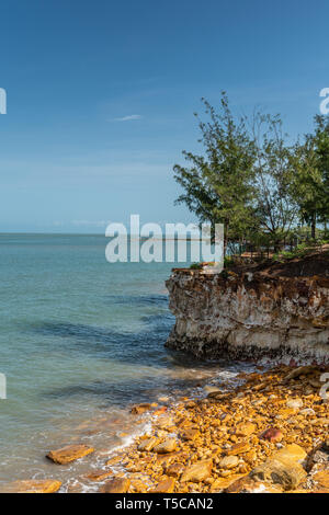 Darwin Australia - Febbraio 22, 2019: spiaggia ghiaiosa a East Point litorale mostra marrone, giallo e scure scogliere rocciose coperte da vegetazione verde und Foto Stock