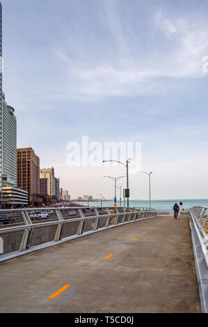 Un ciclista è a cavallo sul cavalcavia di fronte lago lungo Lake Shore Drive. Strade principali in Chicago, strade in Illinois. Foto Stock