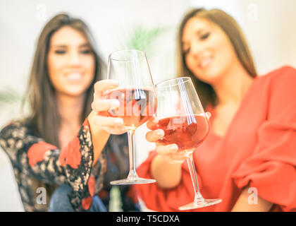 Giovani donne tostatura di bicchieri di vino rosato nella loro casa - Happy ragazze godendo il loro tempo insieme a bere cocktail e divertirsi a ridere Foto Stock