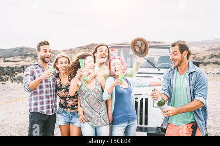 Gruppo di amici felice facendo parte nel deserto - Viaggi persone avendo divertimento bere champagne prosecco durante il loro viaggio con auto JEEP Foto Stock