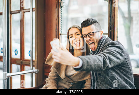 Felice coppia giovane di scattare le foto utilizzando mobile smart phone fotocamera dentro l'autobus - gli amanti di viaggio facendo un autoritratto di post sui social media network Foto Stock