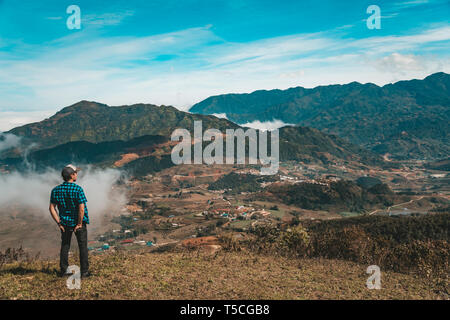 Giovani viaggiatori e permanente alla ricerca in vista della natura di Sapa, il Vietnam nella stagione piovosa. l uomo in montagna cercando la distanza Foto Stock