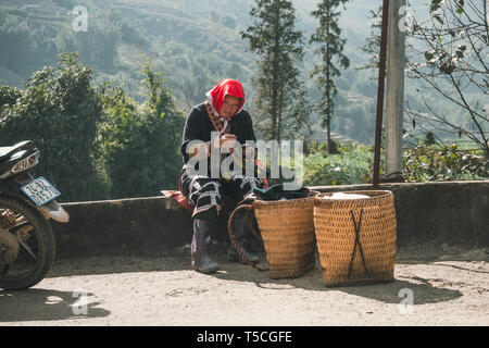 Red dzao minoranza etnica donna cucito in Sa Pa, Lao Cai provincia, Vietnam. donna anziana rende souvenir sulla strada. TA PHIN, LAO CAI, VIETNAM - 12 Foto Stock