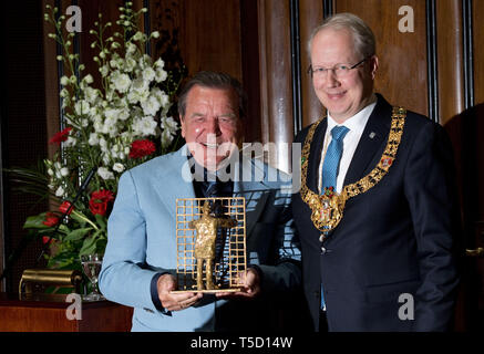 24 aprile 2019, Bassa Sassonia, Hannover: Stefan Schostok (SPD, r), Sindaco di Hannover, presenta l'ex cancelliere tedesco Gerhard Schröder (l) con un opera d arte come un dono in occasione di un ricevimento della città di Hannover per contrassegnare Schröder il settantacinquesimo compleanno nel nuovo municipio. La scultura in bronzo dello scultore Siegfried Neuenhausen, che mostra un uomo di fronte a un recinto, è stato destinato a ricordarci come Schröder, come un giovane membro del parlamento dopo un pub di sera, ha scosso la recinzione della Cancelleria di Bonn con le parole "Voglio andare in là". Foto: Julian Stratenschulte/dpa Foto Stock