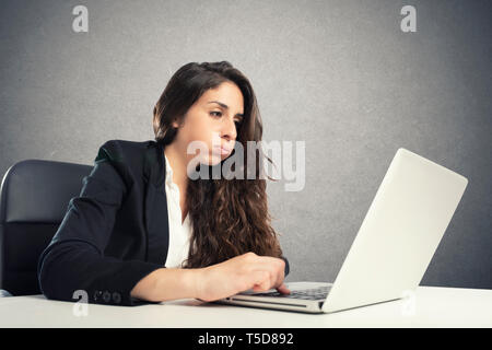 Annoiato donna snorts in ufficio mentre si lavora sul computer portatile Foto Stock
