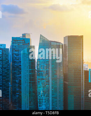 Lo skyline di Singapore, grattacieli di architettura moderna in retroilluminato al tramonto Foto Stock