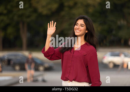 Donna felice saluto e agitando la mano, dicendo ciao Foto Stock