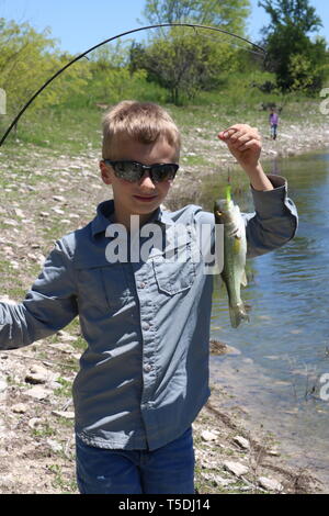 Ragazzo con orgoglio sfoggiano il pesce ha catturato Foto Stock