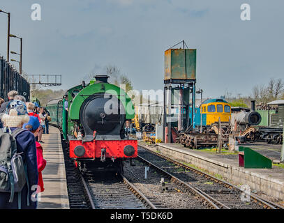 Un verde brillante treno a vapore arriva alla piattaforma per prendere il prossimo viaggio Foto Stock